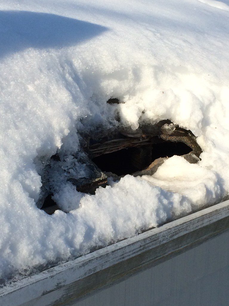 Snow-covered roof with a hole