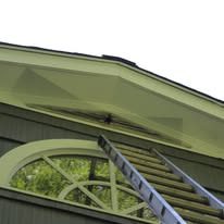 Ladder leaning on house eaves above arched window