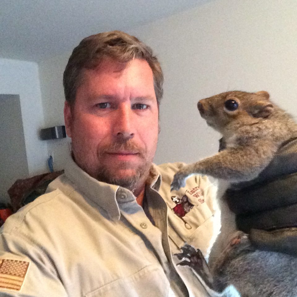 Man holding a squirrel indoors