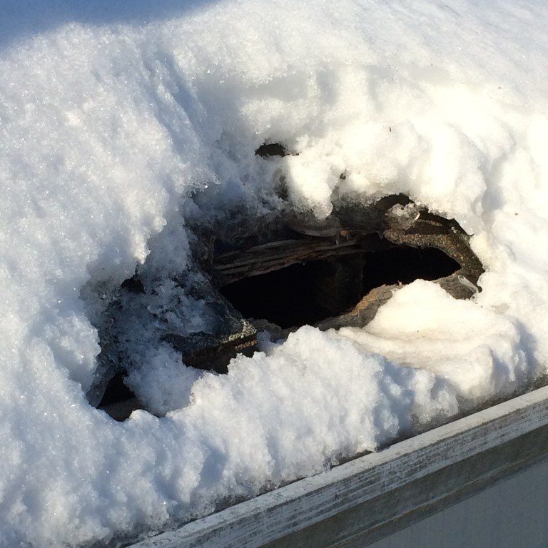 Snow-covered roof with a hole