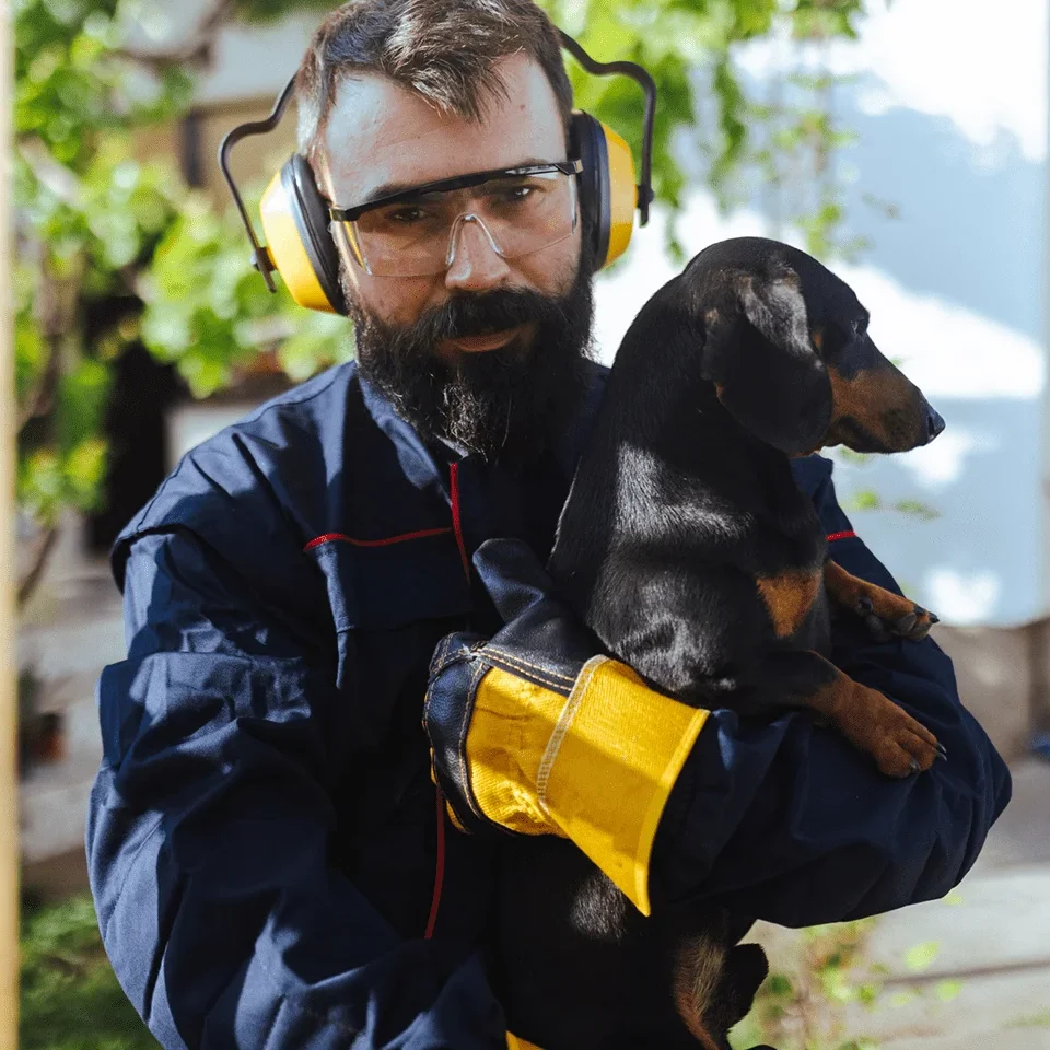 Man holding dachshund wearing protective gear