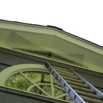 Ladder leaning on house eaves above arched window